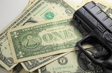 Dollars with a pistol on top representing Pay-for-Slay